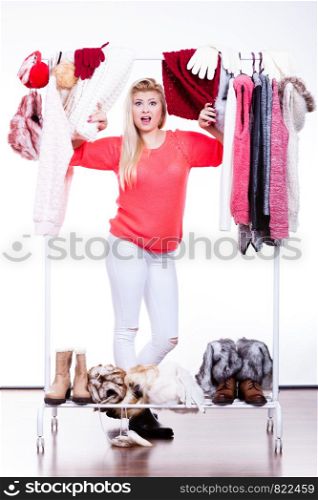 Woman standing in wardrobe with winter clothes, can not decide what to wear. Picking winter clothing concept.. Woman in winter wardrobe deciding what wear