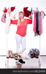 Woman standing in wardrobe with winter clothes, can not decide what to wear. Picking winter clothing concept.. Woman in winter wardrobe deciding what wear