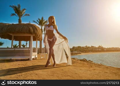 Woman standing nearby Cabana with straw roof on a sandy beach on sunny day at Red Sea.. Woman standing nearby Cabana with straw roof on a sandy beach on sunny day at Red Sea