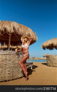 Woman standing nearby Cabana with straw roof on a sandy beach on sunny day at Red Sea.. Woman standing nearby Cabana with straw roof on a sandy beach on sunny day at Red Sea