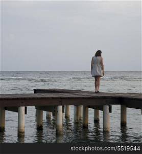 Woman standing on a pier and looking at sea, Utila Island, Bay Islands, Honduras