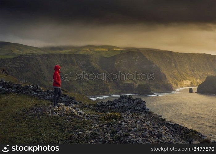 Woman standing on a top of a clif and enjoying the view, Azores Island.
