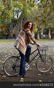 Woman standing on bicycle in park