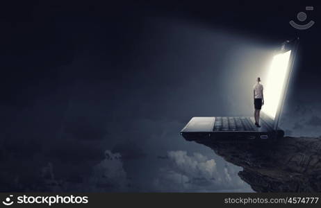 Woman standing on big laptop. Rear view of businesswoman with suitcase standing on keyboard of big laptop