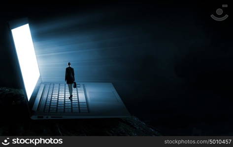 Woman standing on big laptop. Rear view of businesswoman with suitcase standing on keyboard of big laptop