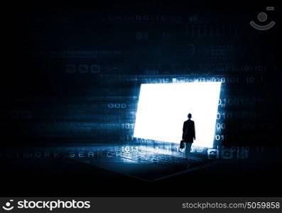Woman standing on big laptop. Rear view of businesswoman with suitcase standing on keyboard of big laptop