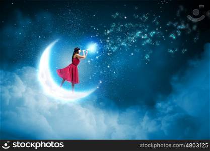 Woman standing on moon. Young woman in red dress playing flute