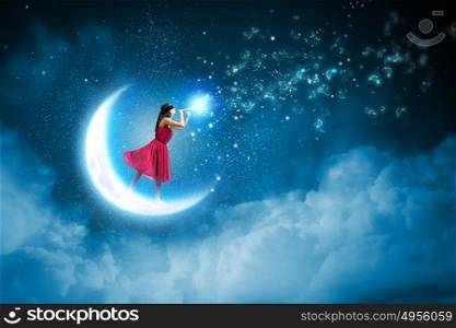 Woman standing on moon. Young woman in red dress playing flute