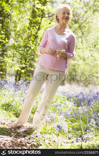 Woman standing outdoors holding flower smiling