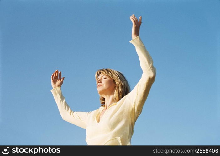 Woman standing outdoors with arms up