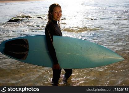 Woman standing with a surfboard smiling