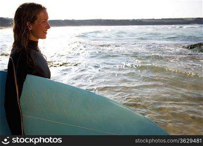 Woman standing with a surfboard smiling