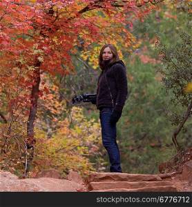 Woman standing with a tripod in a forest, Zion National Park, Utah, USA
