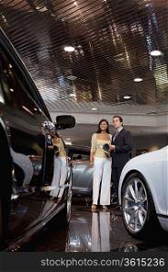 Woman standing with auto salesman in showroom
