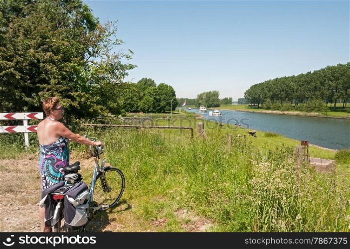 woman standing with bike looking at the boats going by on the river in Holland
