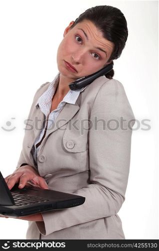 woman standing with phone and laptop