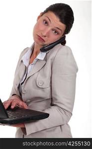 woman standing with phone and laptop