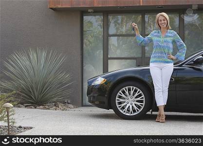 Woman stands holding keys to luxury vehicle