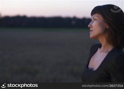 Woman stands in a field at twilight