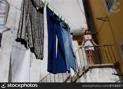 Woman stands on steps with washing in courtyard, Lisbon, Portugal