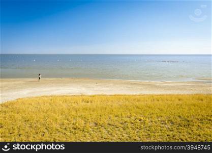 Woman stands on the lake edge looking out over the Makgadikgadi Pan in Botswana, Africa while on safari