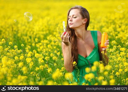 woman start soap bubbles on yellow flower field