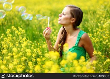 woman start soap bubbles on yellow flower field
