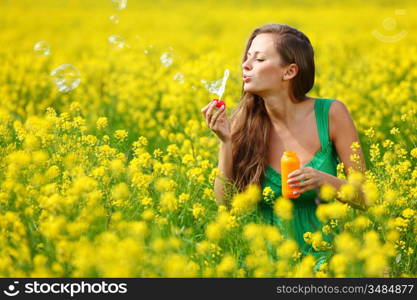 woman start soap bubbles on yellow flower field