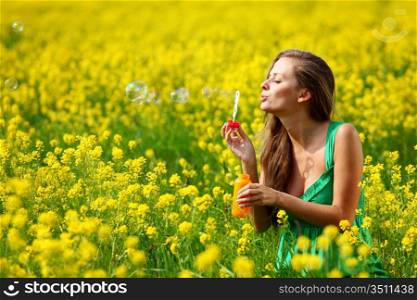 woman start soap bubbles on yellow flower field