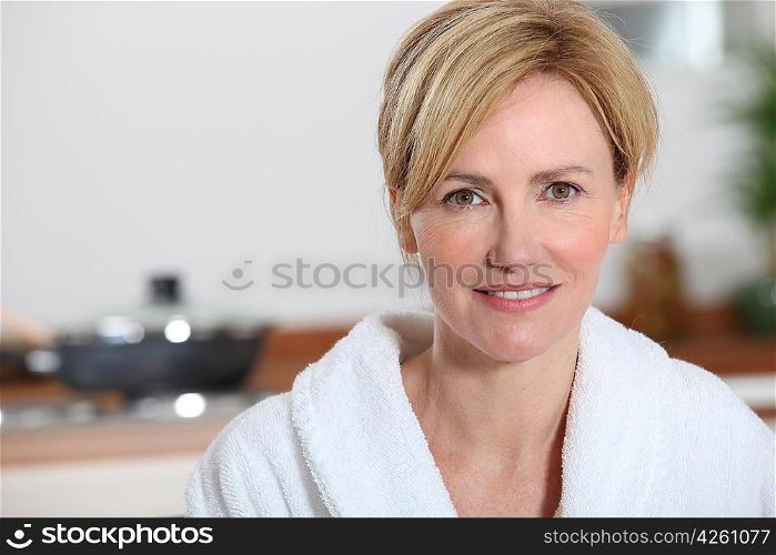 Woman stood in kitchen wearing bathrobe