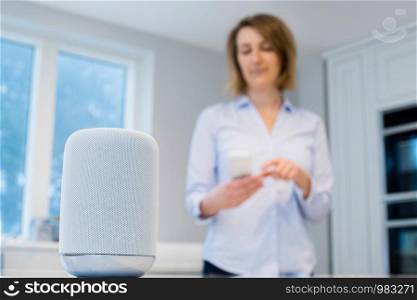 Woman Streaming Music Wirelessly From Mobile Phone To Speaker