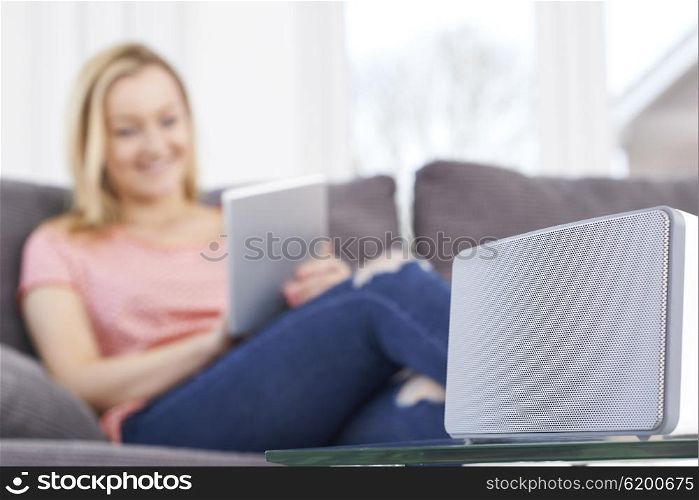 Woman Streams Music From Digital Tablet To Wireless Speaker