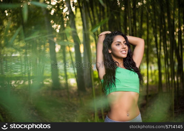 Woman stretching her arms in bamboo garden