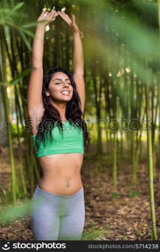 Woman stretching her arms in bamboo garden