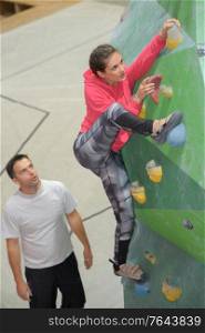 woman stretching leg upwards on indoor climbing wall