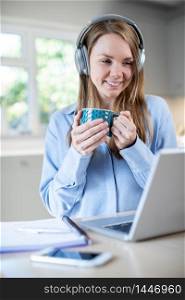 Woman Studying At Home Using Laptop And Wearing Headphones