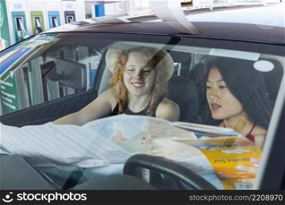 woman studying road map sitting car