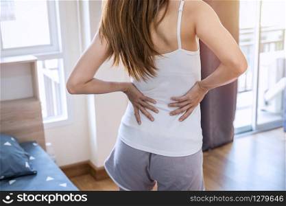Woman suffering from back ache on the bed, healthcare and problem concept. Woman suffering from back ache on the bed