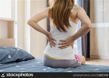 Woman suffering from back ache on the bed, healthcare and problem concept. Woman suffering from back ache on the bed