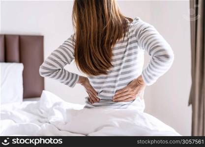 Woman suffering from back ache on the bed in the morning, healthcare and problem concept