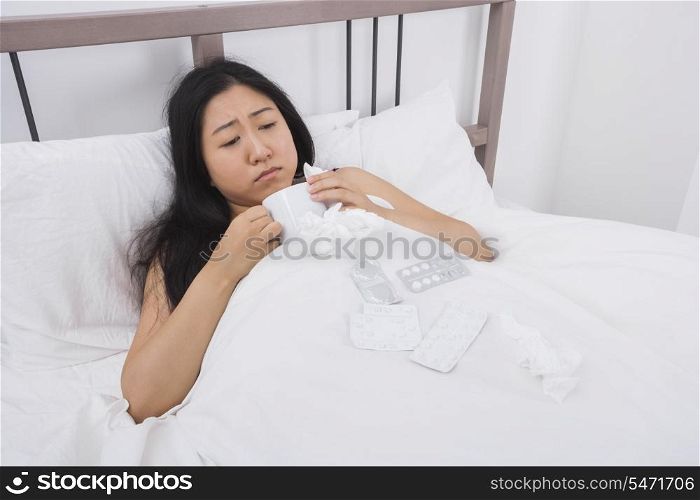 Woman suffering from cold having coffee in bed