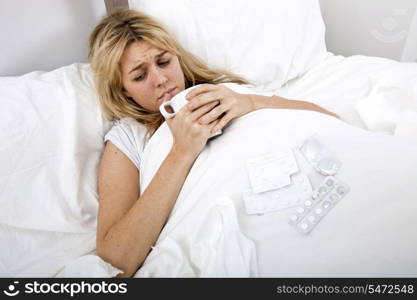 Woman suffering from cold having coffee in bed