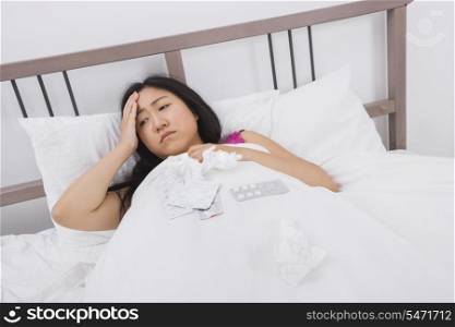 Woman suffering from headache and cold lying in bed