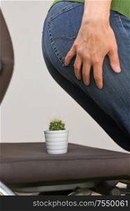 Woman Suffering From Hemorrhoids And Thorny Cactus on chair