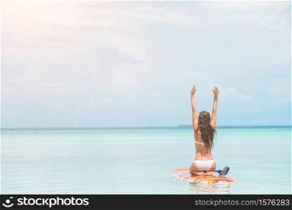 Woman surfing on stand up paddle board on summer vacation. Woman surfing in the sea on vacation