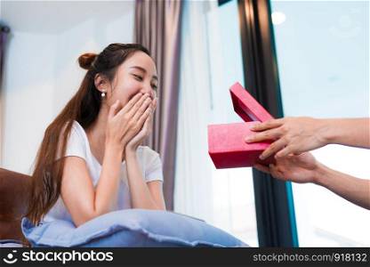 Woman surprised when looking at gift box on special day. Lovers and honeymoon concept. Happiness and Valentines day theme.