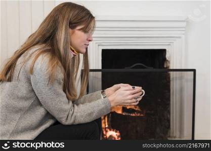 woman sweater drinking tea near fireplace