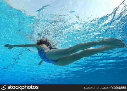 Woman swimming in pool underwater view