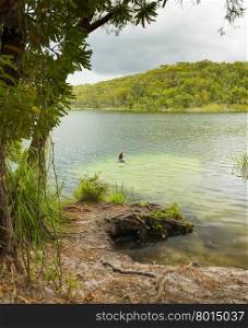 Woman swimming in the perfect fresh water swimming hole Blue Lake on North Stradbroke Island, Queensland, Australia
