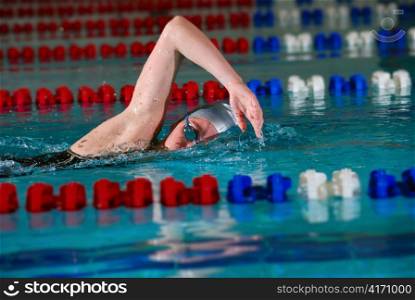 woman swims using the crawl stroke in indoor pool